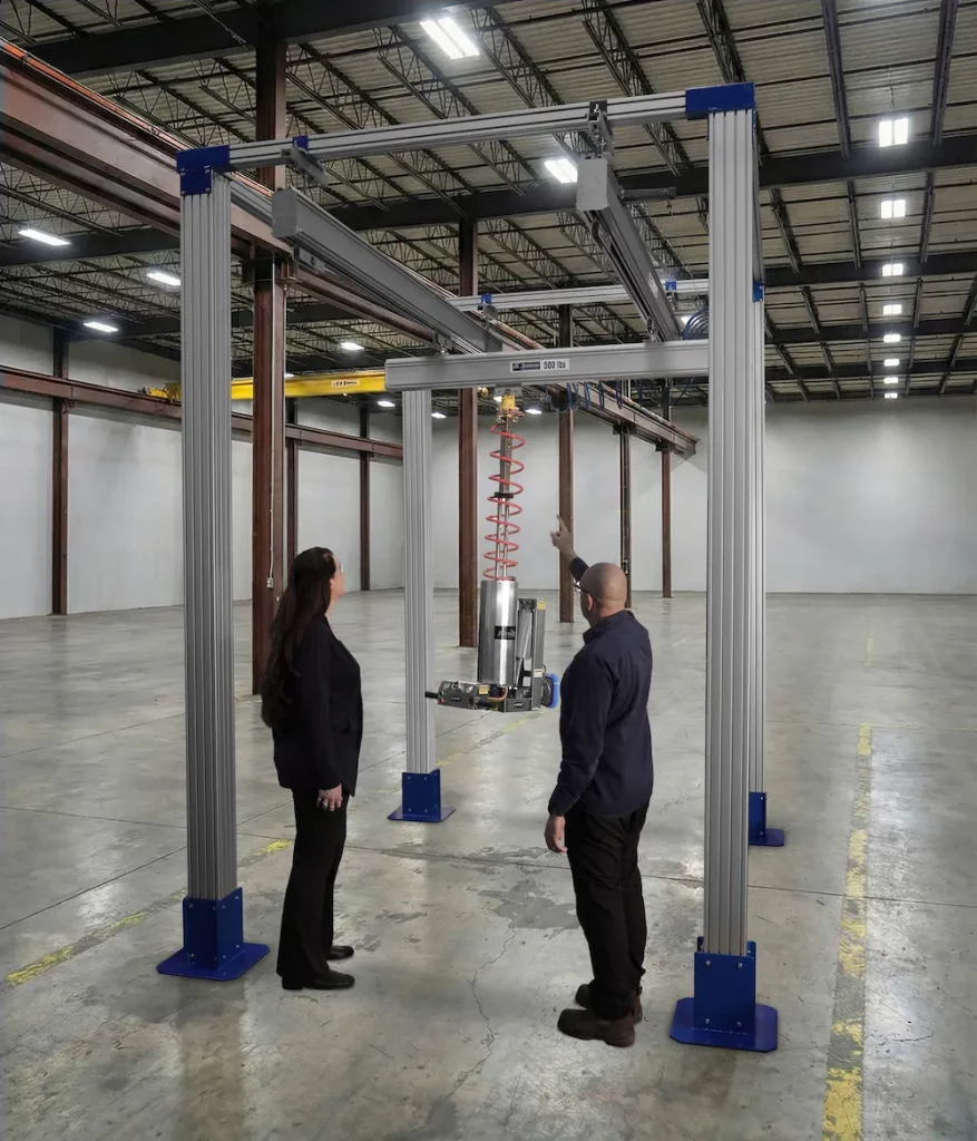 Workstation crane (AL SYSTEM™) in an empty warehouse with team discussing